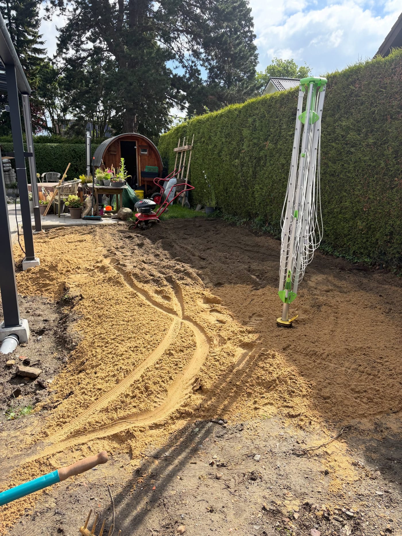 Sand wird in den Gartenboden eingefräst, Fräse im Hintergrund
